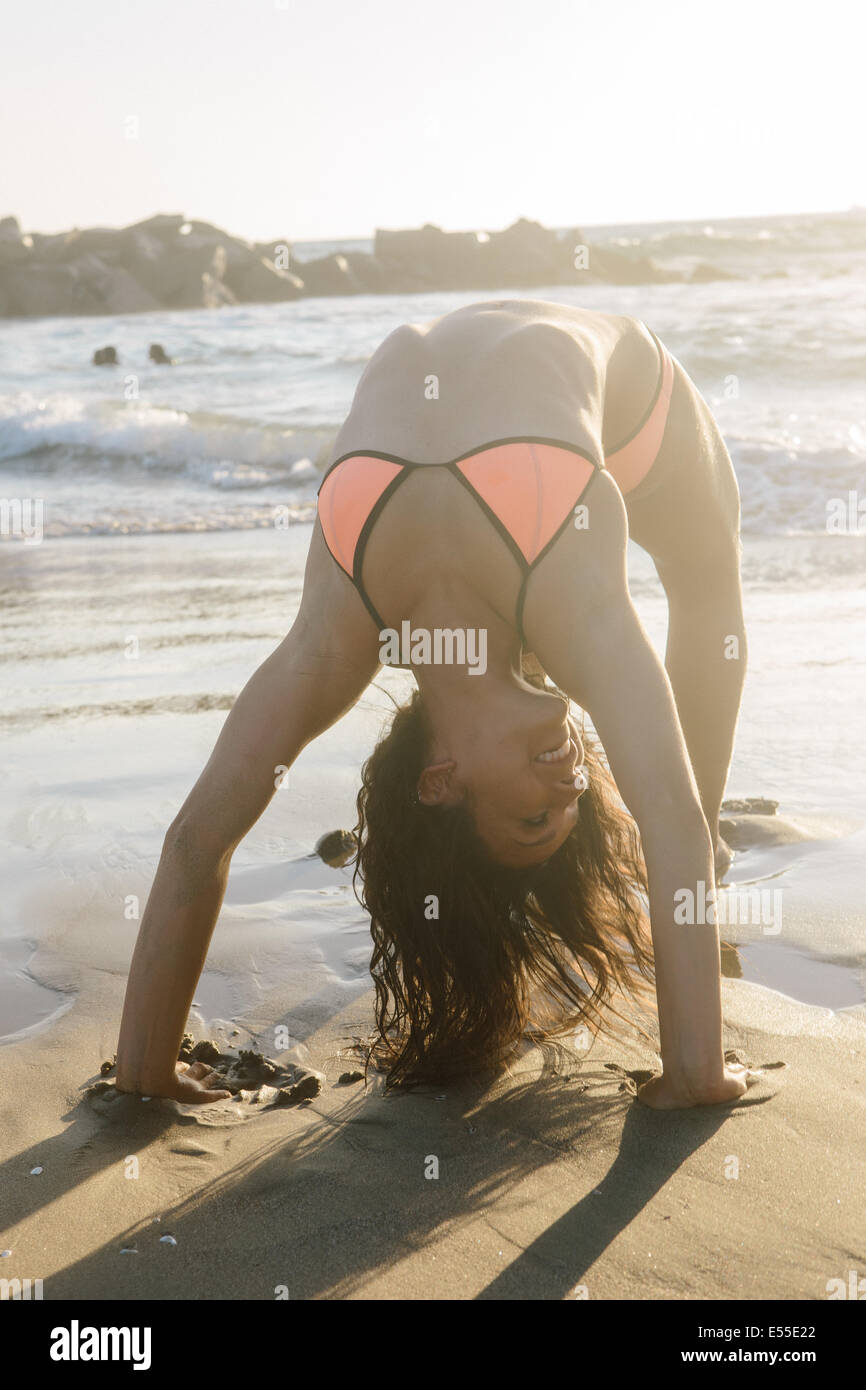 Fit young female in a bikini doing a backbend on the beach Stock Photo -  Alamy