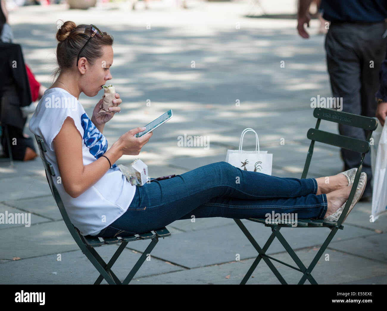A woman reads using an ereader in Bryant Park in New York on Friday, July 18, 2014.  (© Richard B. Levine) Stock Photo
