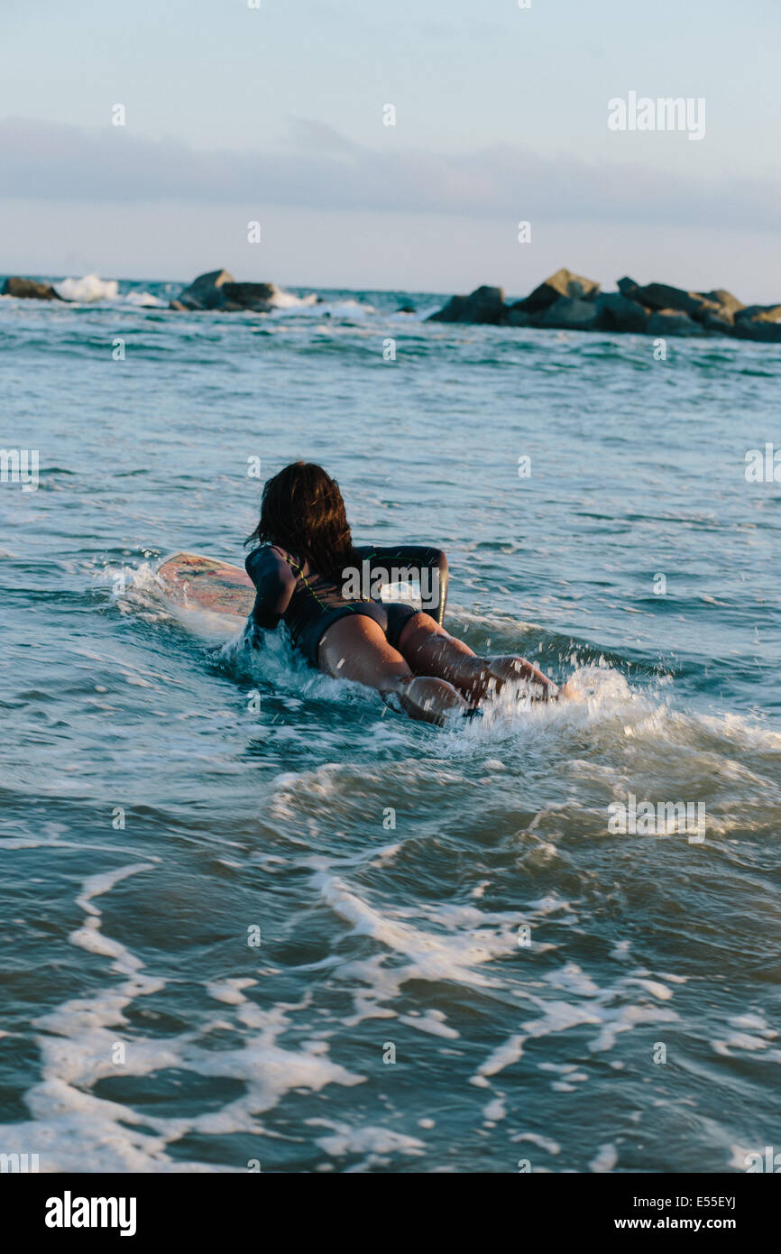 Fit female surfer padding into ocean Stock Photo