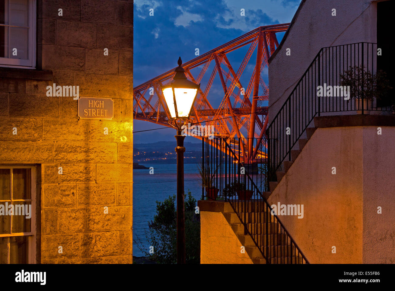A shot of the Forth Rail Bridge through a gap in the cobbled High Street in South Queensferry at dusk. Stock Photo