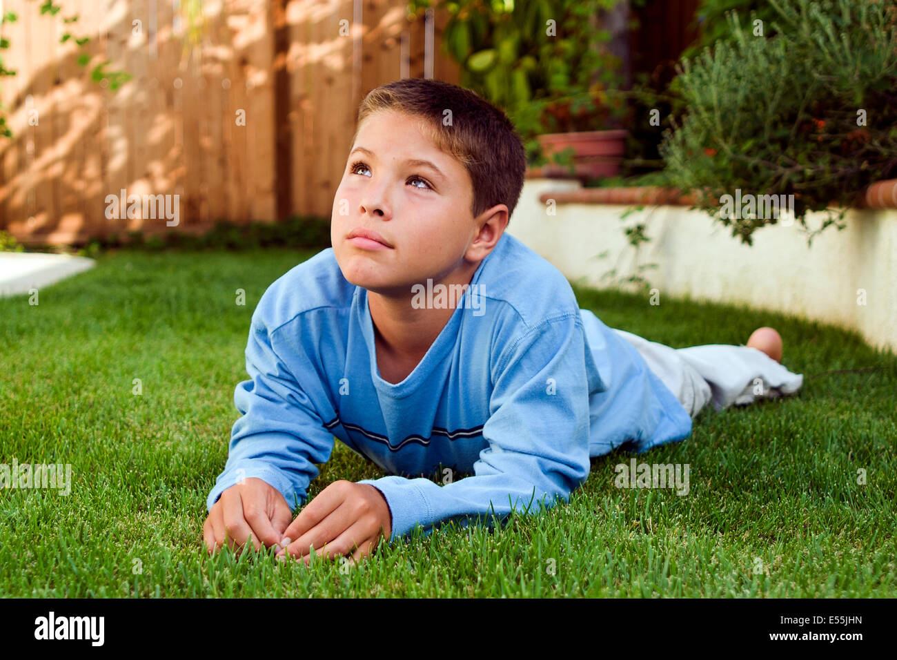 9-10 year old young person people Japanese/Caucasian boy laying on grass thinking thoughtful dreaming sitting reflecting in backyard. MR © Myrleen Pearson Stock Photo