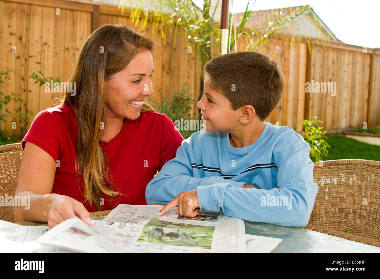 Ethnic mother and 9-10 years old son child children reading newspaper in backyard. MR © Myrleen Pearson Stock Photo
