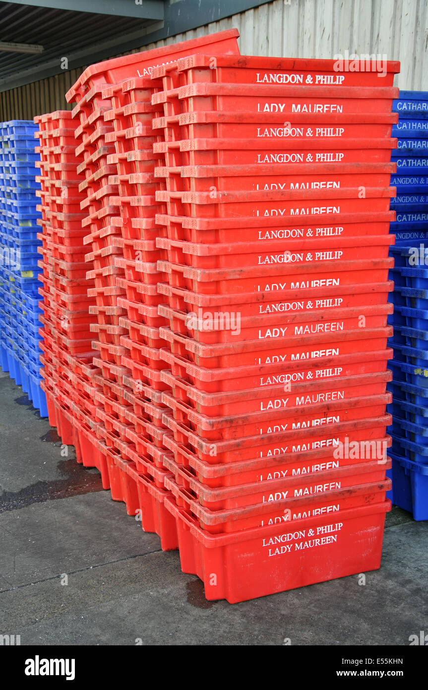 red plastic fish containers stacked on quayside, Brixham harbour, Devon, England, UK Stock Photo