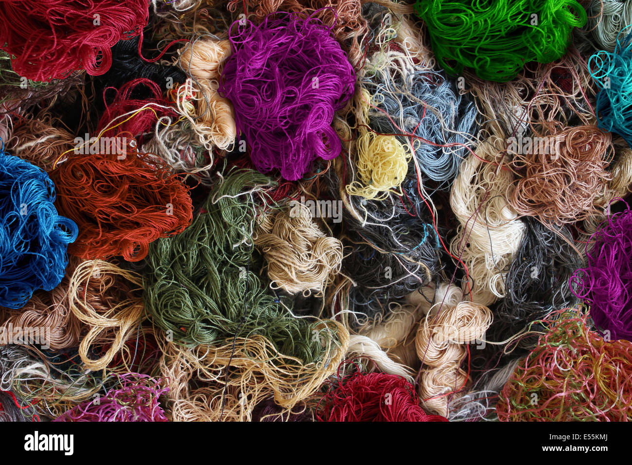 Textile industry background as a group of multi colored entangled sewing threads as a symbol for the fashion industry and clothing business or garment manufacturing as a heap of fibers. Stock Photo