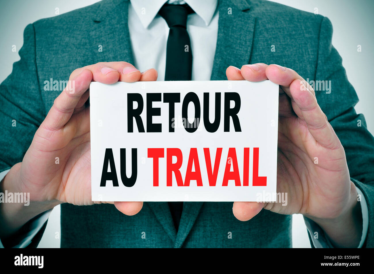 businessman holding a signboard with the text retour au travail, back to work in french, written in it Stock Photo