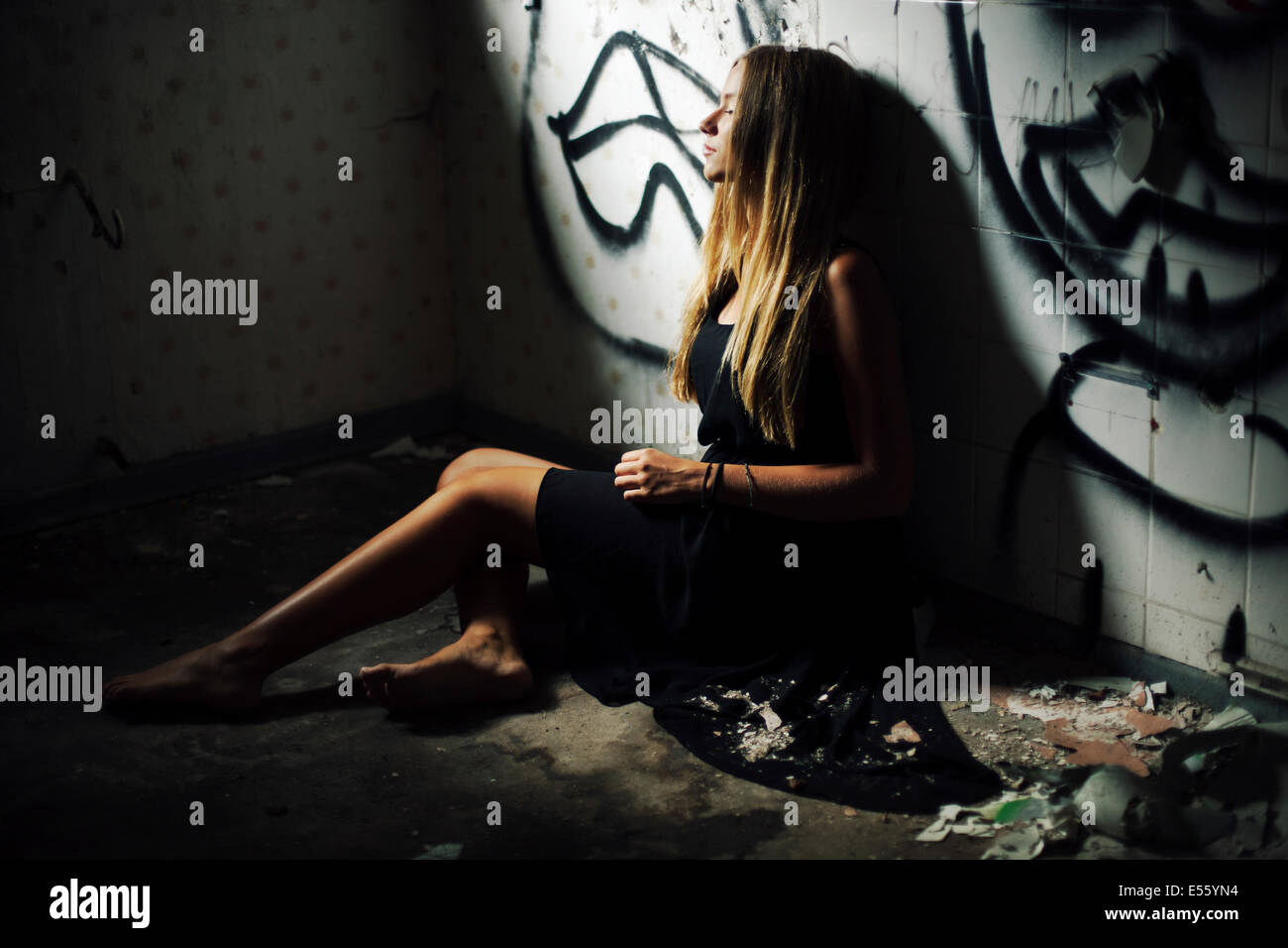 Young woman sitting on dirty floor Stock Photo