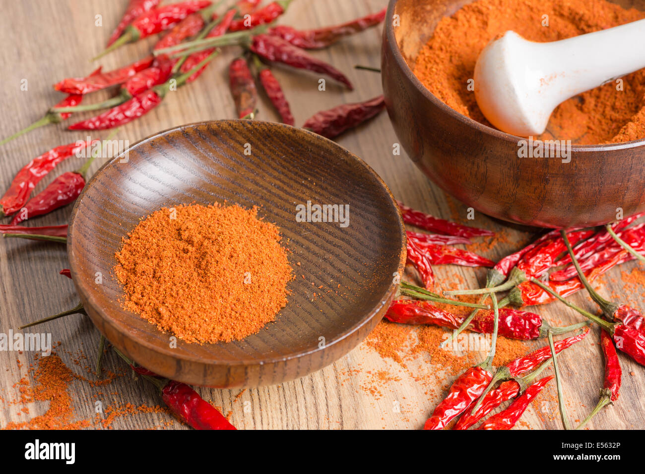 red hot pepper chili powder in a mortar and pods on a wooden table Stock Photo