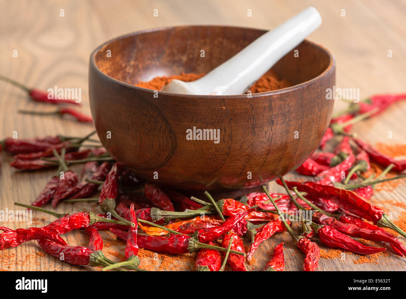 red hot pepper chili powder in a mortar and pods on a wooden table Stock Photo