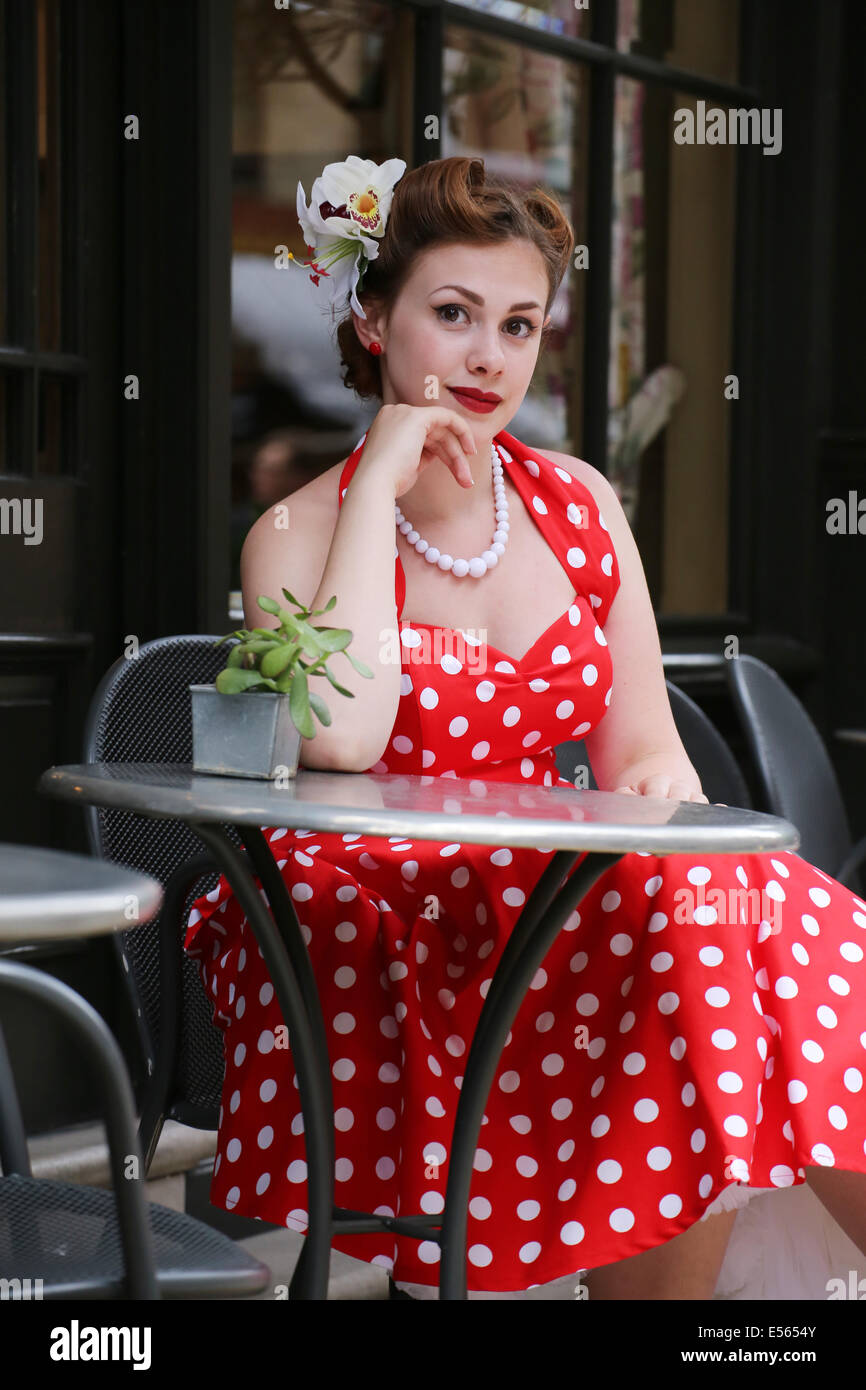 Girl in a red polka dot dress sitting in a cafe Stock Photo