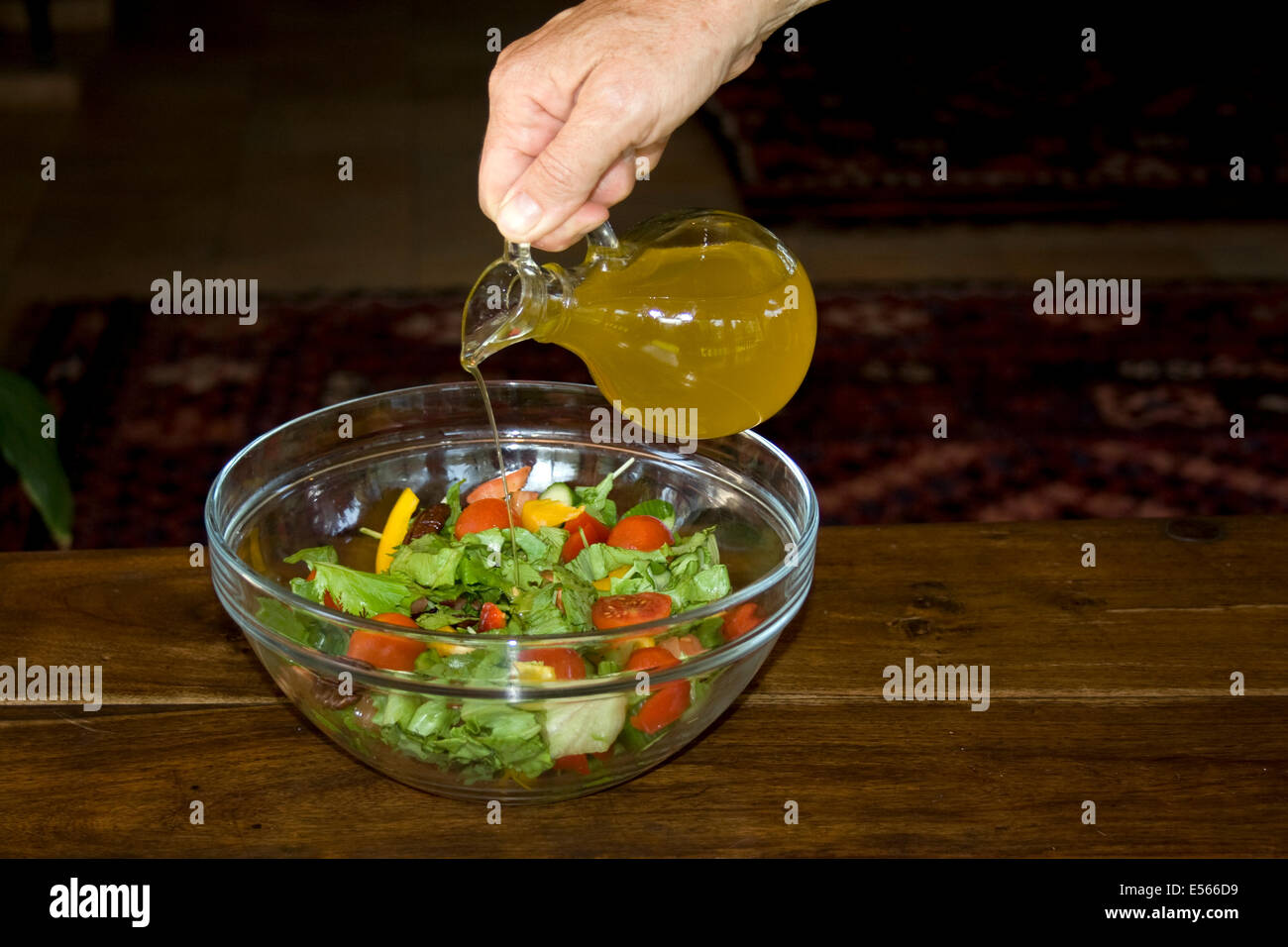 Adding virgin olive oil to a salad Stock Photo