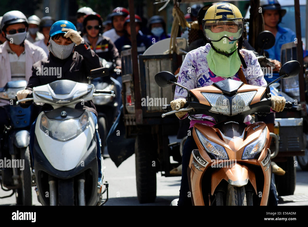 Commuters riding scooters and wearing pollution masks, Ho Chi Minh