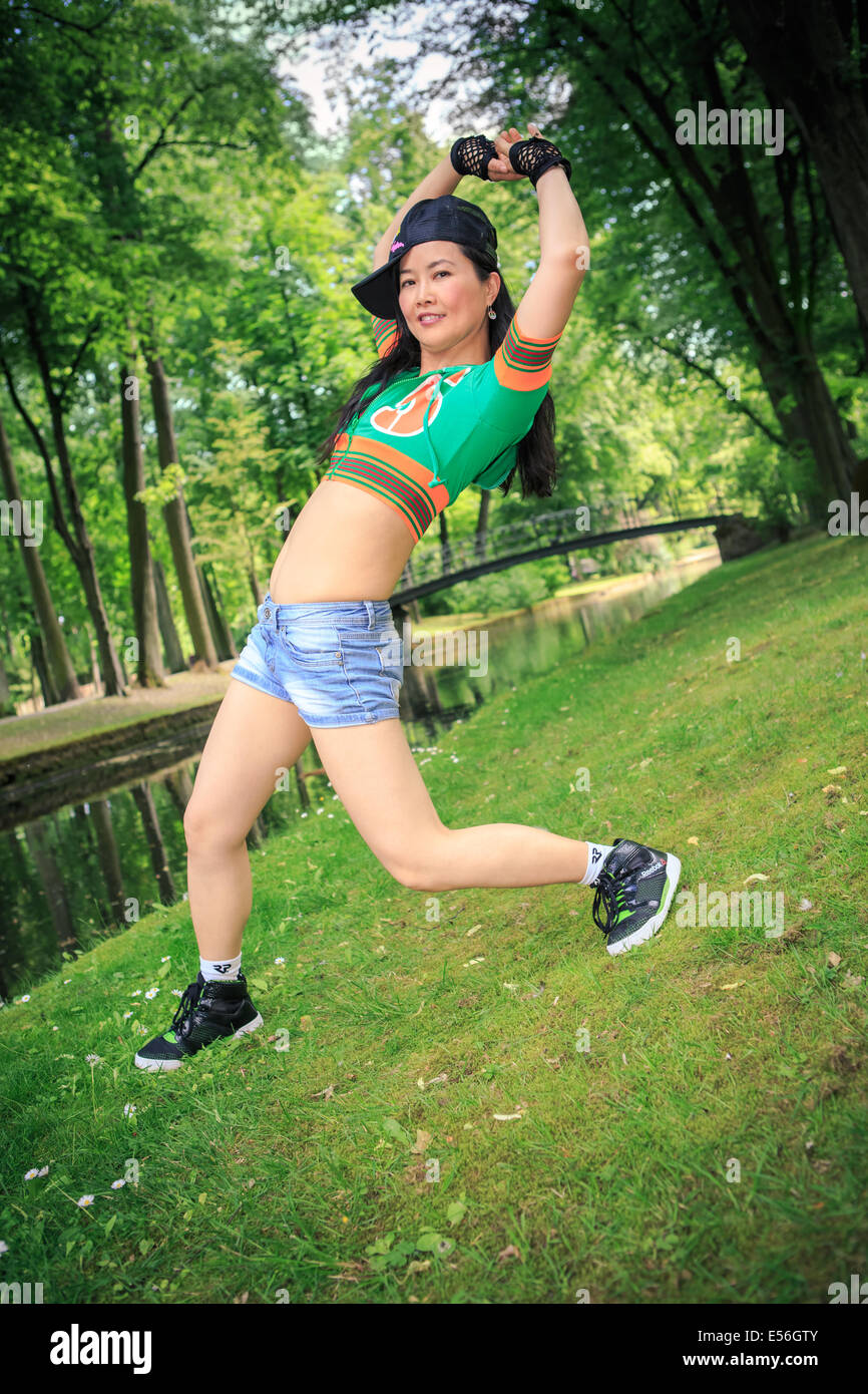 young woman in sport dress dancing in reggaeton or hiphop style in the park Stock Photo