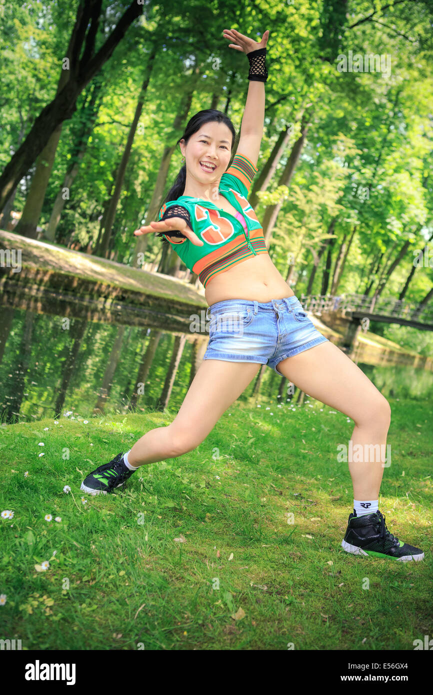 young woman in sport dress dancing in reggaeton or hiphop style in the park Stock Photo