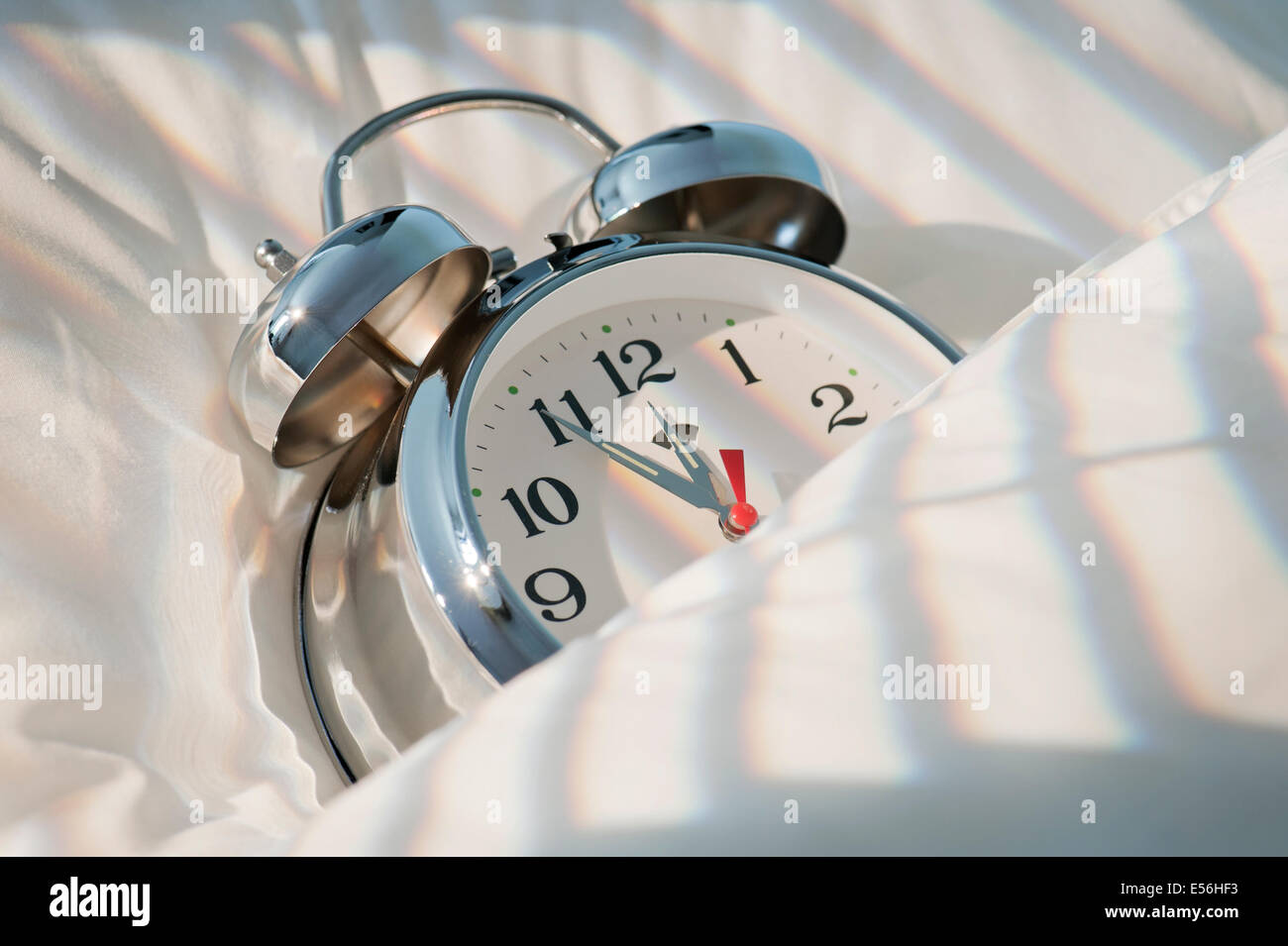 classical alarm clock sleeping on bed until noon with sunlight Stock