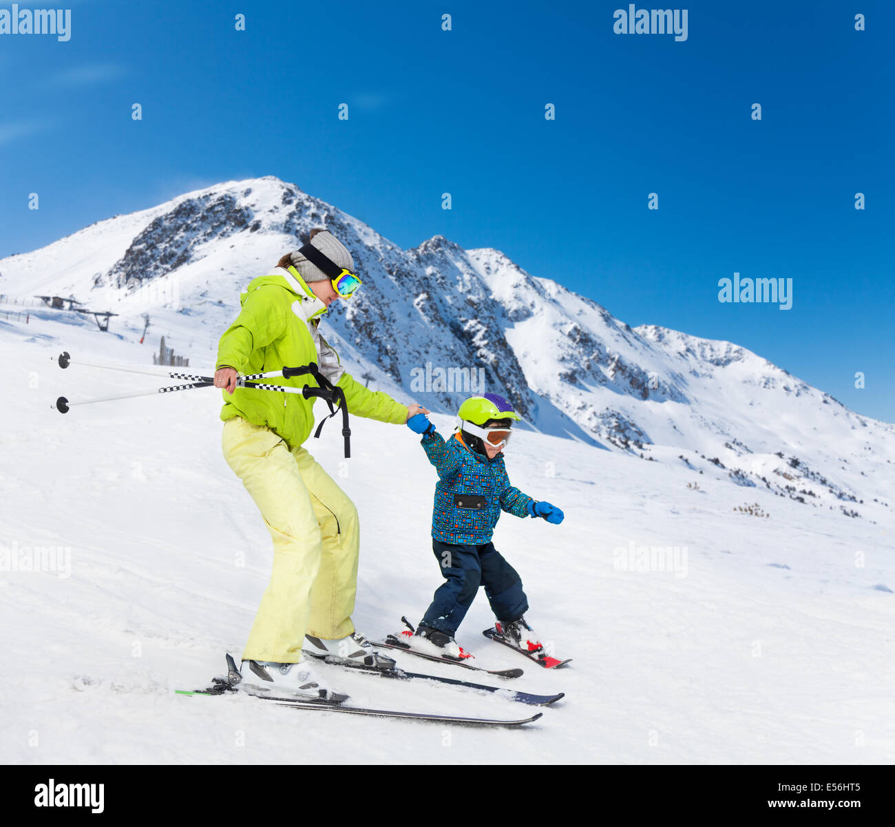 Instructor and kid skiing down the mountain Stock Photo