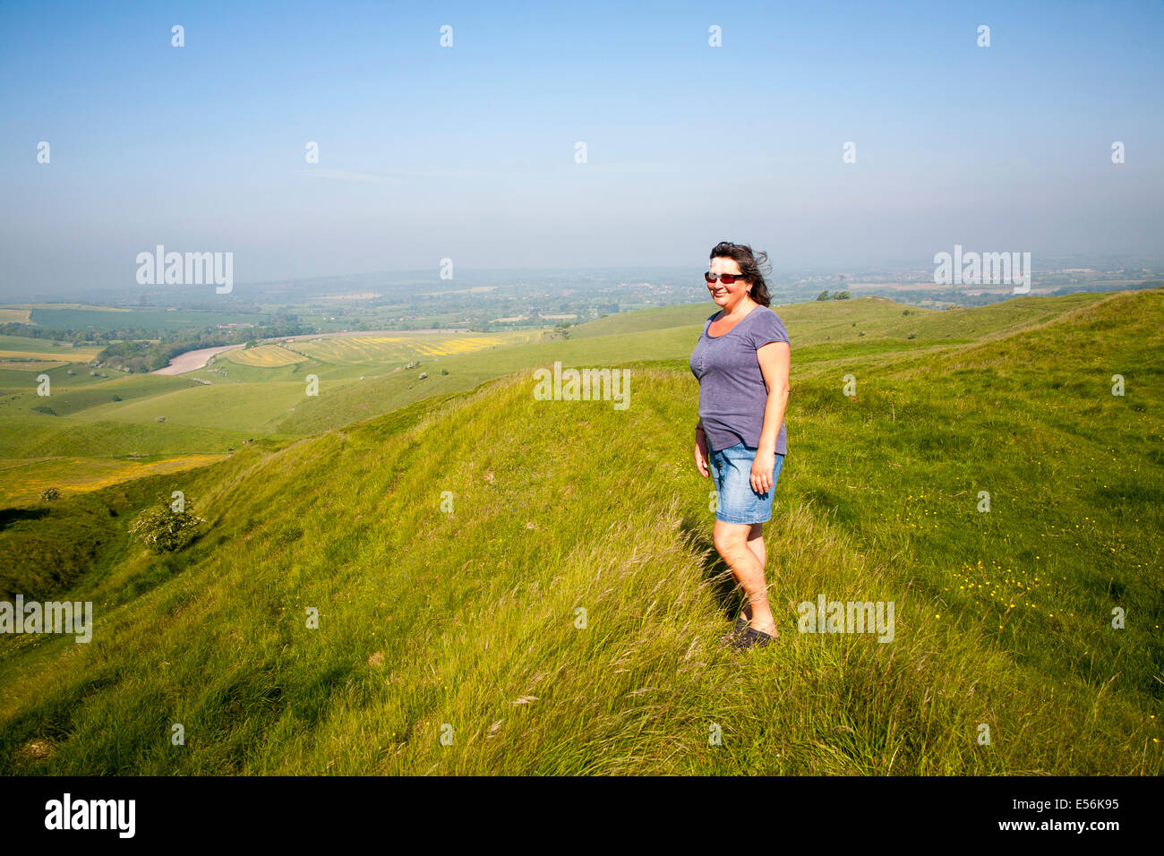 Woman standing on steep chalk scarp slope on downland at Cherhill Down, Wiltshire, England Stock Photo