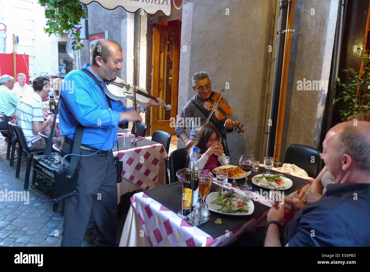 Musicians serenade people eating at a restaurant, In Rome, Italy. Stock Photo