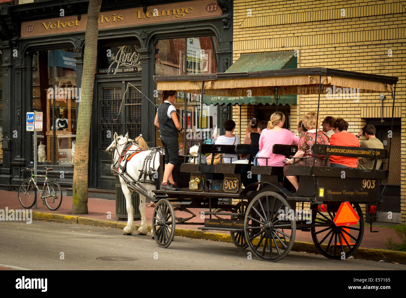 Tourist enjoy a stop at the Velvet Elvis Lounge while aboard their horse drawn carriage in Savannah, GA, USA Stock Photo
