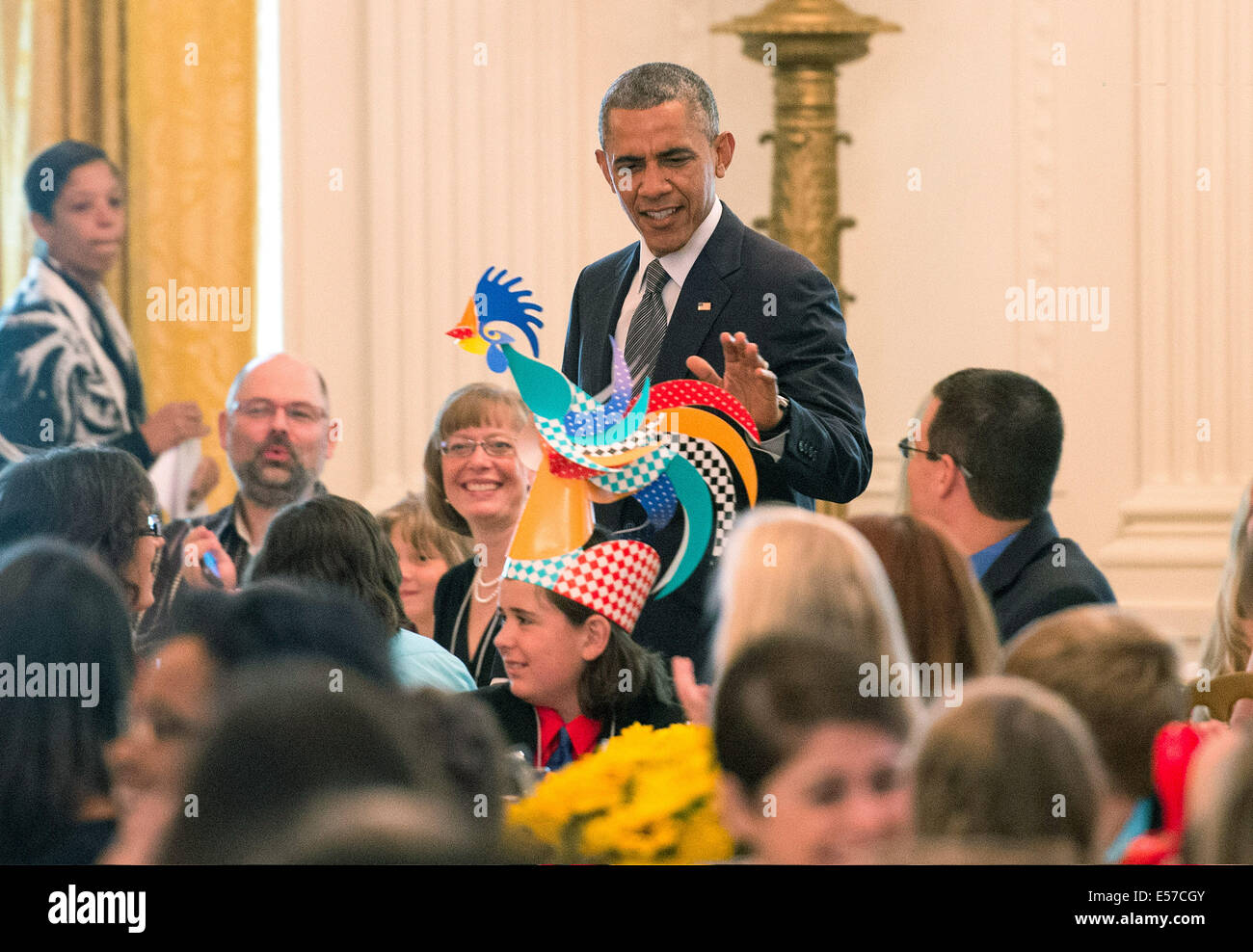 United States President Barack Obama looks at a child's hat as he arrives at the Kids' State Dinner in the East Room at the White House on July 18, 2014 in Washington, DC Credit: Kevin Dietsch/Pool via CNP Stock Photo