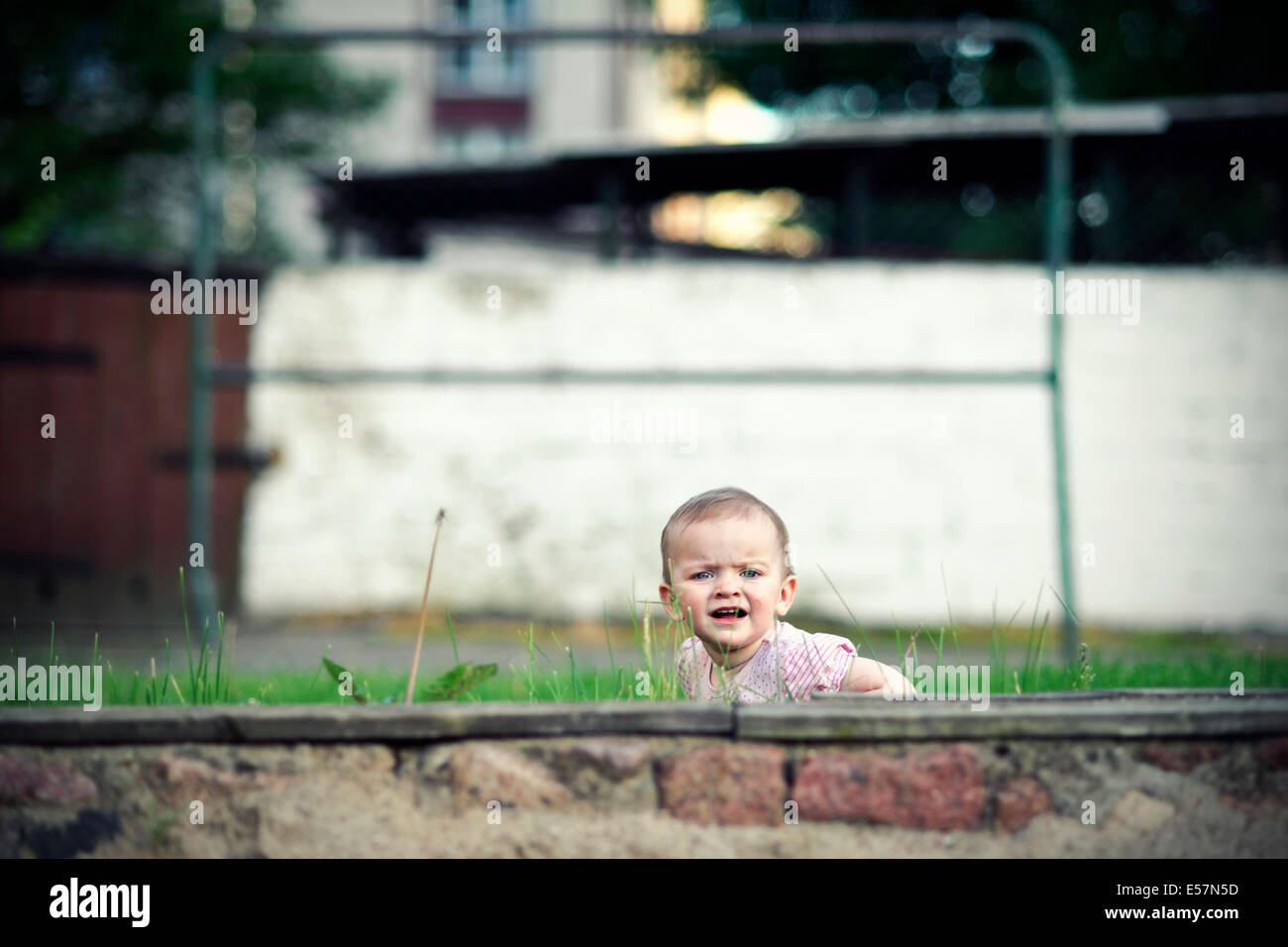 Little girl hiding behind small wall on playground Stock Photo Alamy