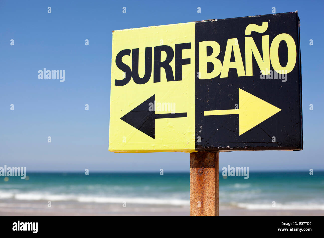 black and yellow arrow surf swimming bano sign on Spanish beach with white waves sand blue skies Stock Photo