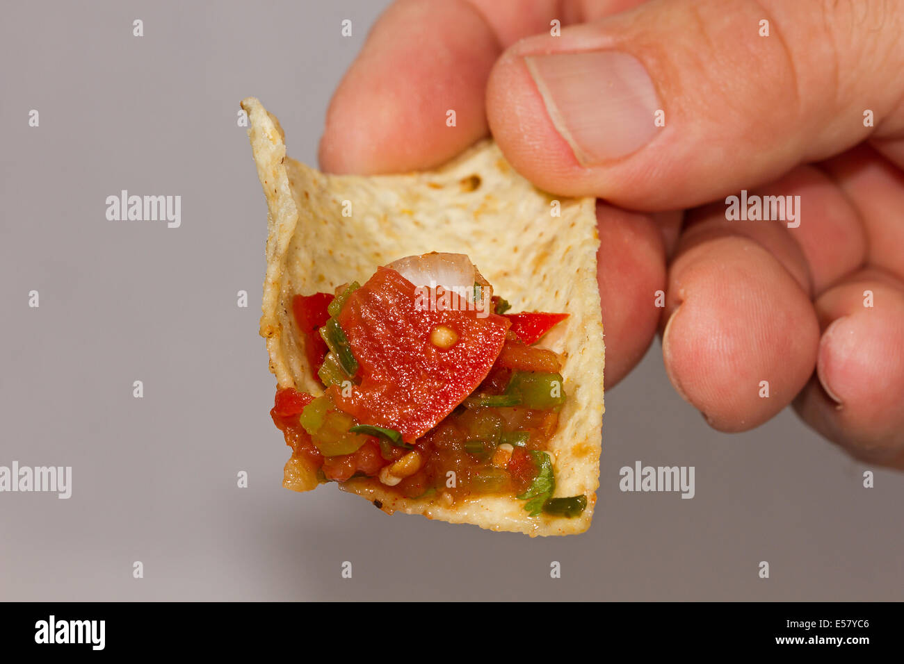 Hand holding tortilla chip and salsa. Stock Photo