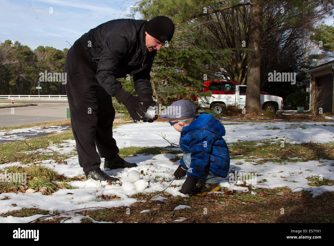 Family snow fun, Dad teaching his little son to make snowballs. Stock Photo