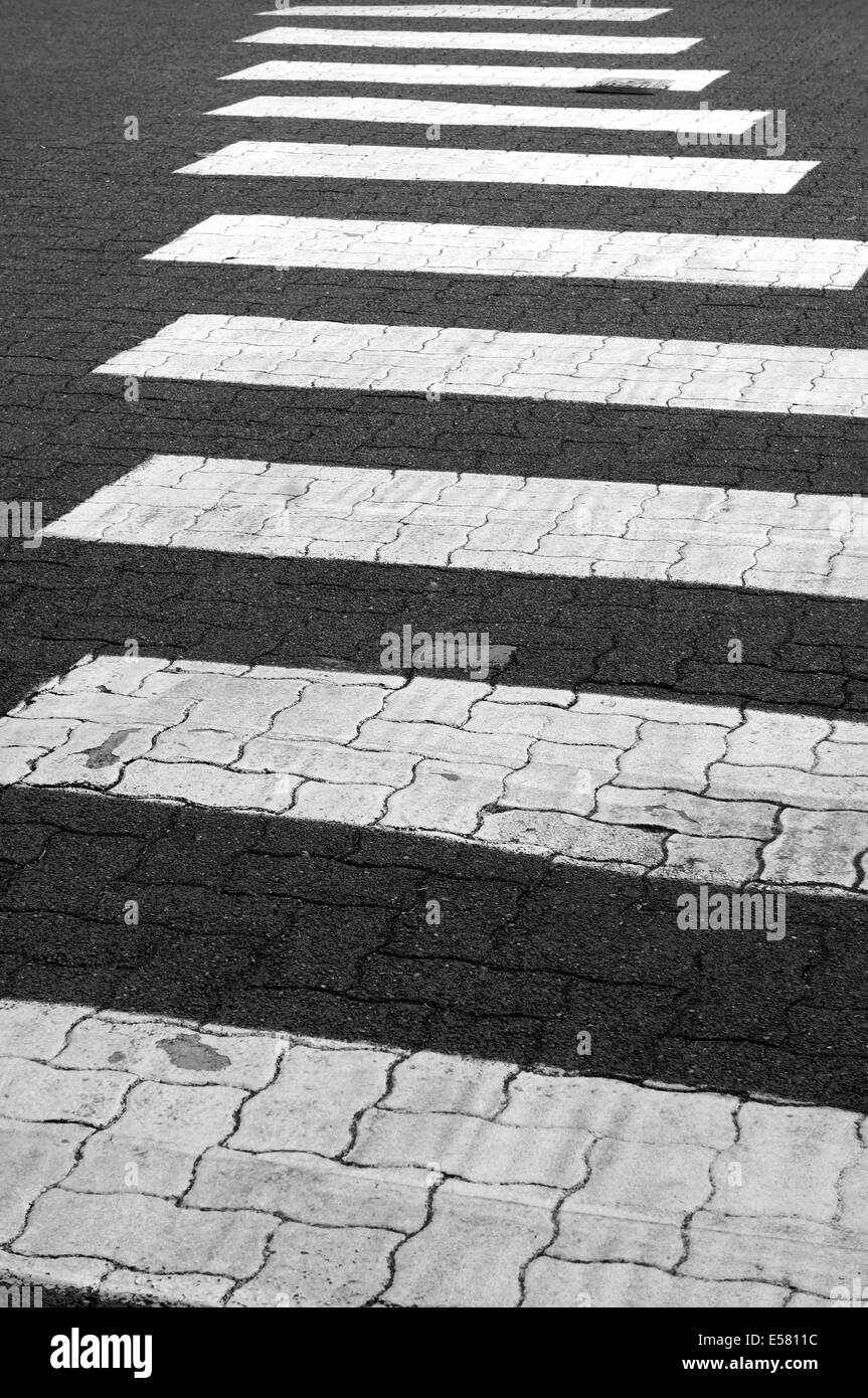 Black and white image of receding white lines on pedestrian crosswalk Stock Photo
