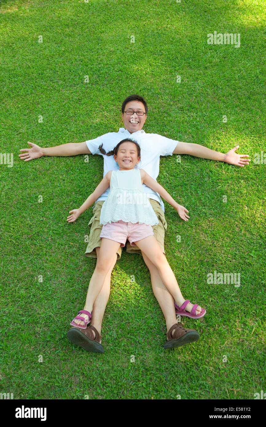 father and daughter lying on a meadow together Stock Photo