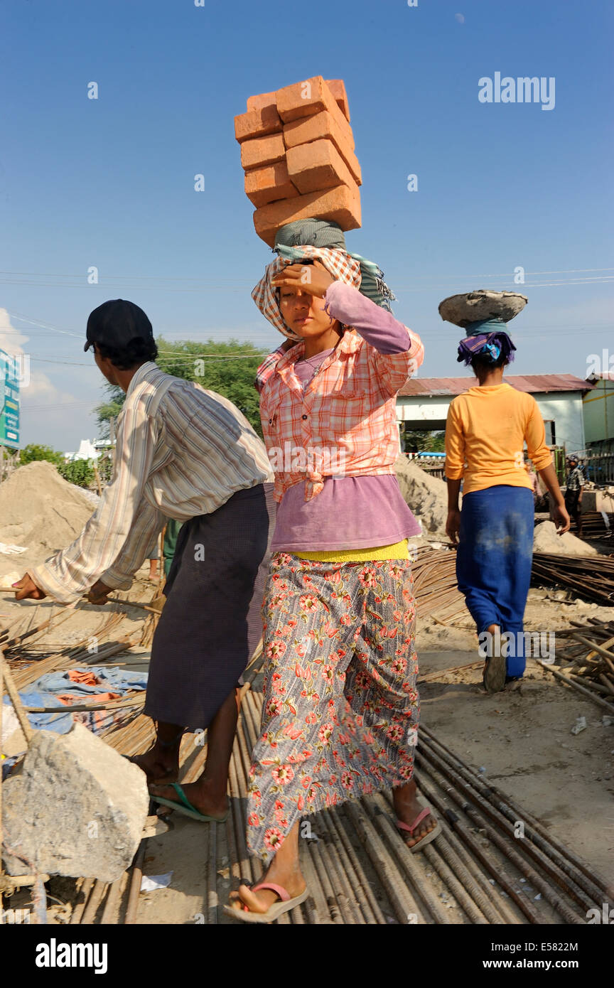 Female construction workers carry bricks on their heads, high rise construction site, Mandalay, Myanmar Stock Photo