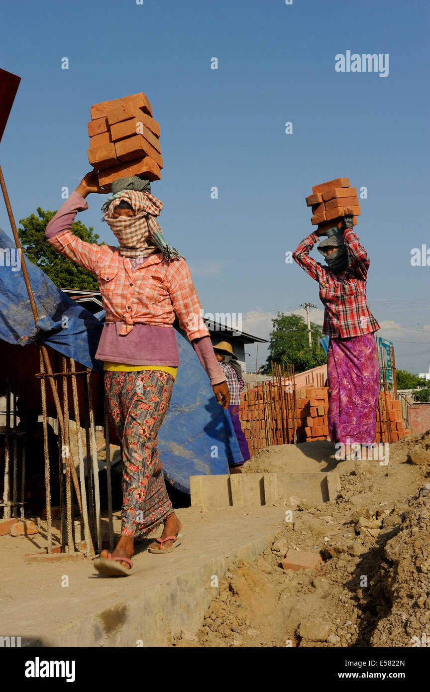 Female construction workers carry bricks on their heads, high rise construction site, Mandalay, Myanmar Stock Photo