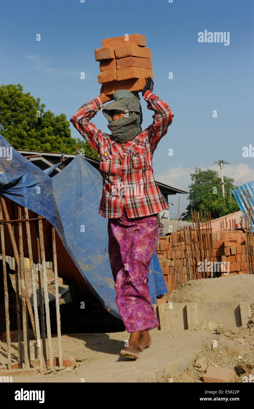 Female construction worker carry bricks on their heads, high rise construction site, Mandalay, Myanmar Stock Photo