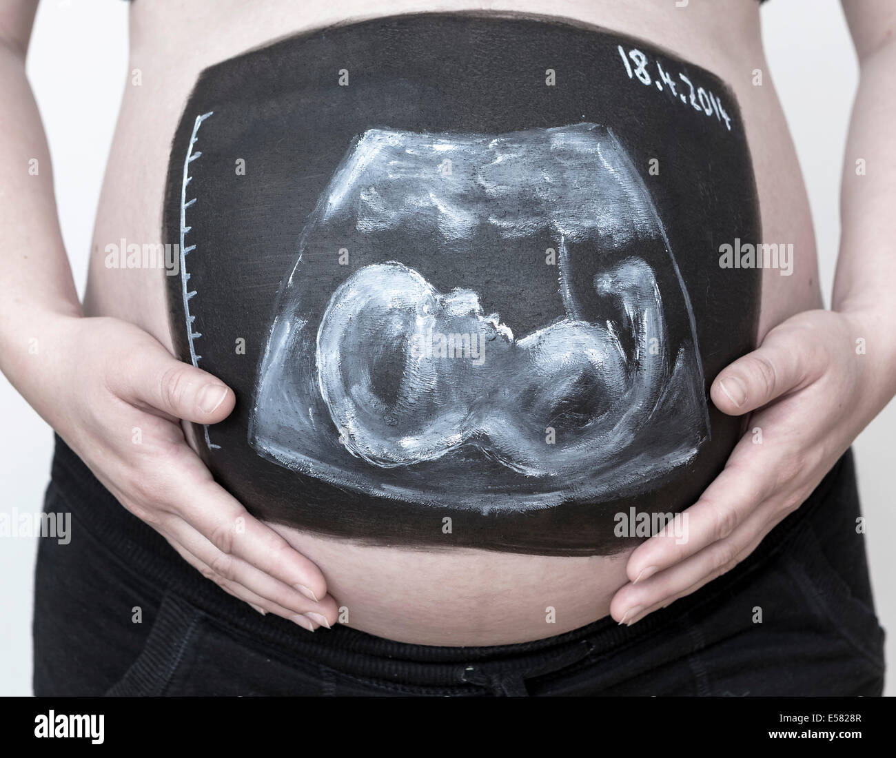 Pregnant woman with a body paint of an ultrasound image on her belly Stock Photo