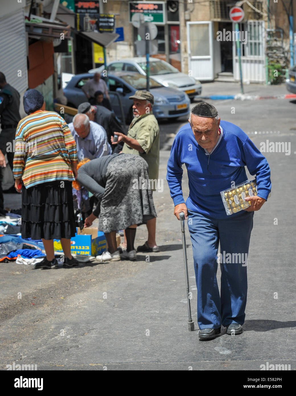 An old man carrying a box of chocolate candies walks towards Machane Yehuda market, Jerusalem, Israel Stock Photo