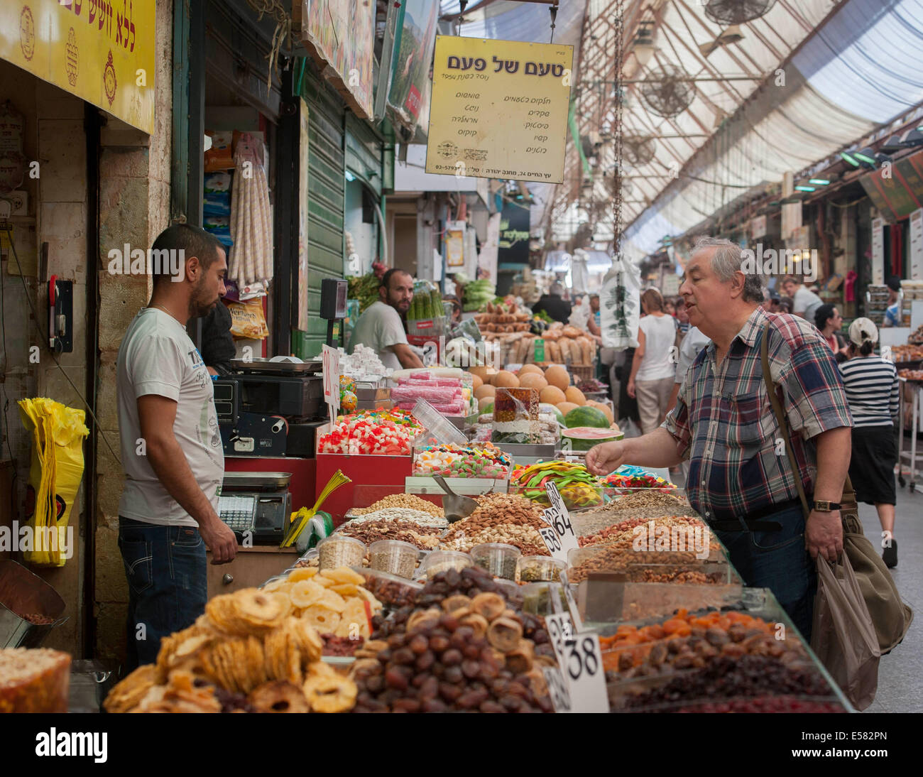 A dried fruit and seeds vendor with shoppers at Machane Yehuda market