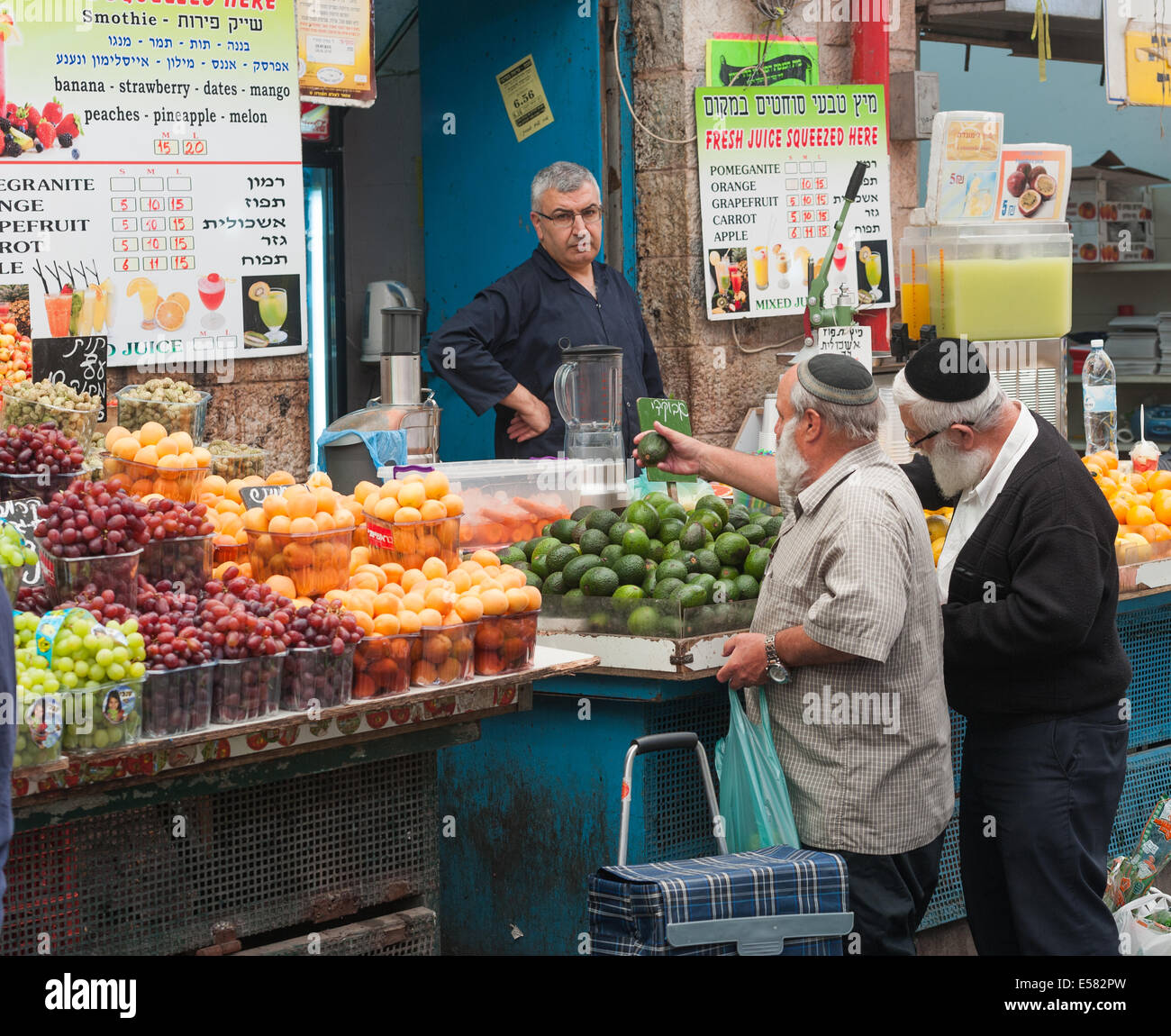 Two shoppers selecting fresh fruit at a fruit stand  at the Machane Yehuda market, Jerusalem, Israel Stock Photo