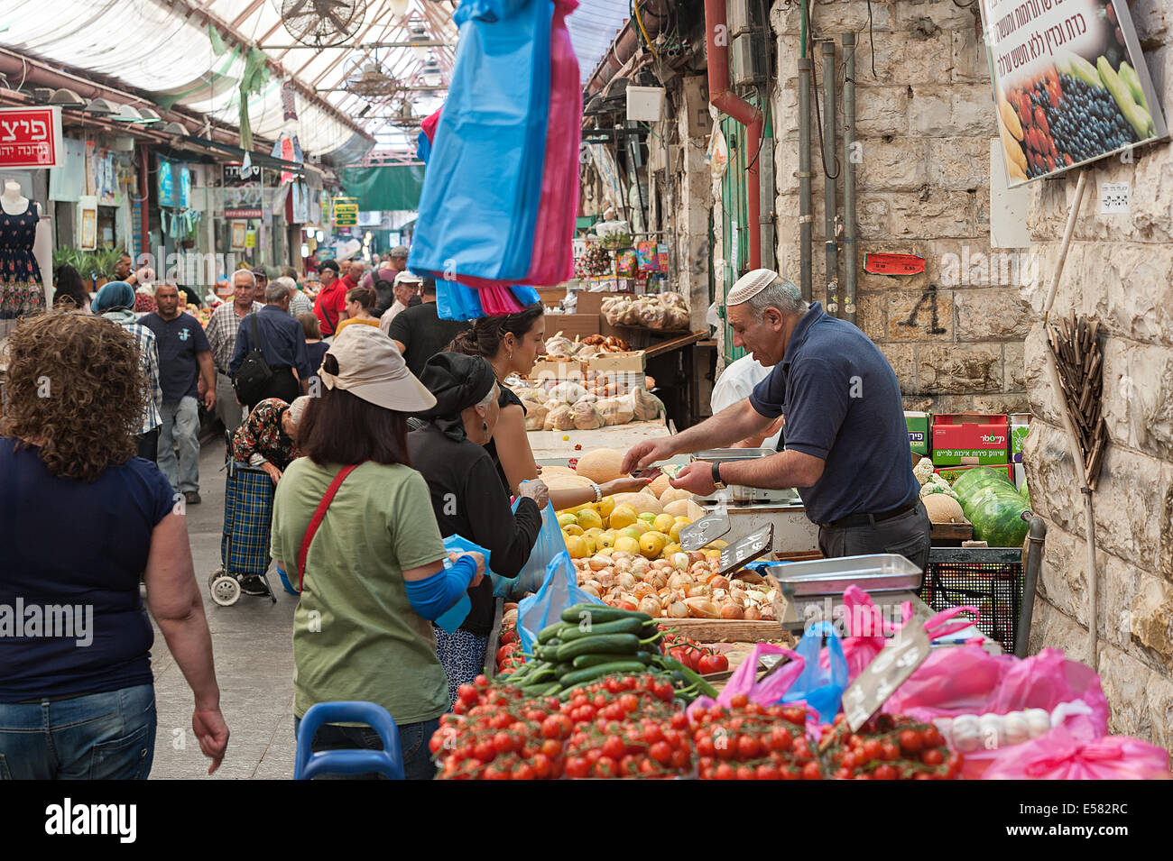 A fruit and vegetable vendor with shoppers at the 'Machane Yehuda' market, Jerusalem, Israel Stock Photo