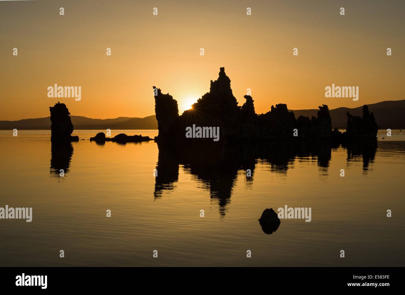 sunrise at Mono Lake over tufa towers with golden sky and reflection in water Stock Photo