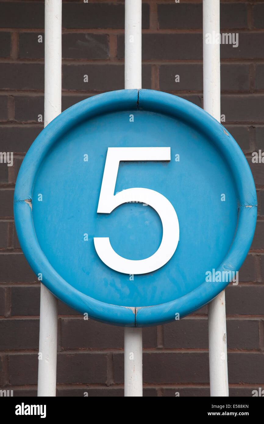Number Five on Blue Circle against Brick Wall and Railings Background ...