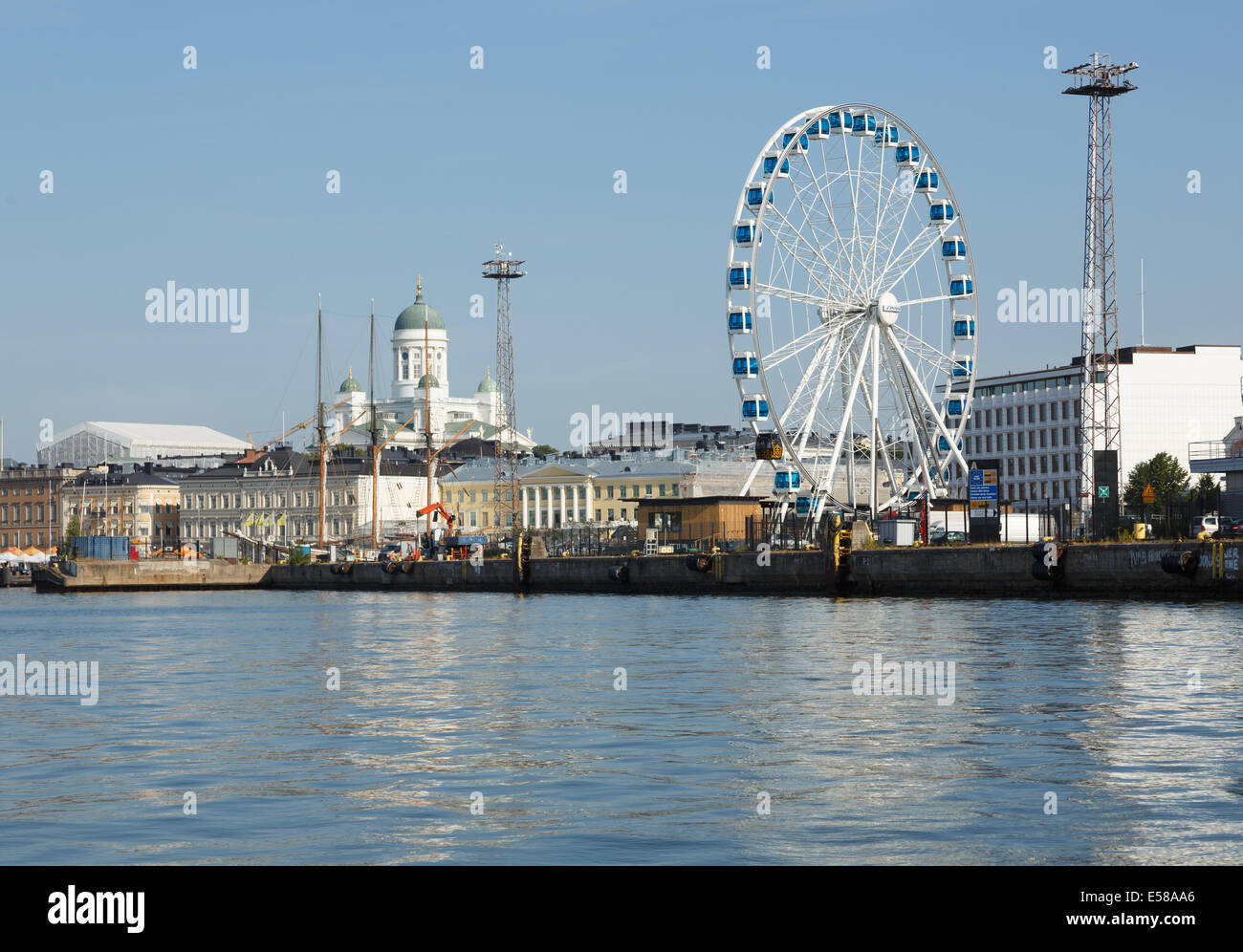 Ferris wheel attracts visitors for a view on the South Harbor of Helsinki, with the Lutheran Cathedral in the background, Stock Photo
