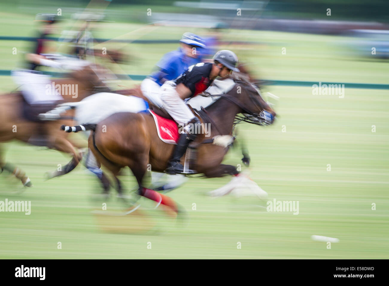 Jonny Good and competitors are blurred as he launches an attack for Clashleigh in a polo match at Cowdray Park. Stock Photo