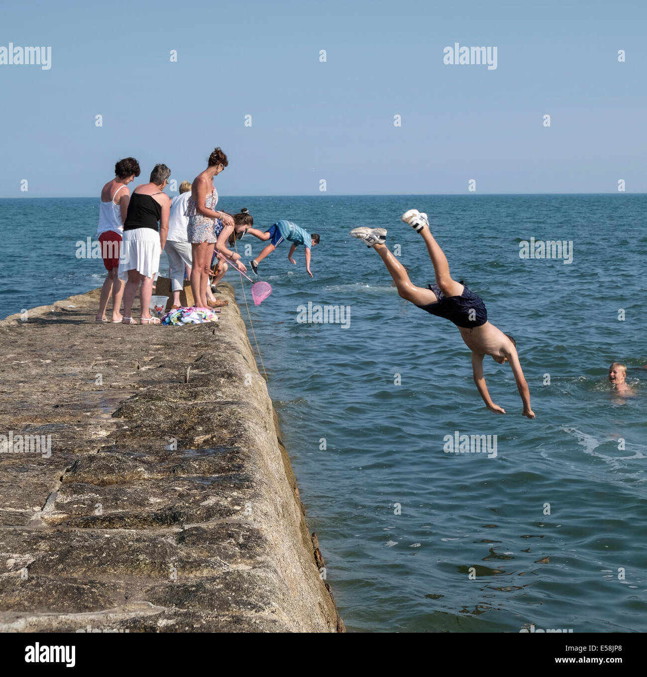 Dawlish, Devon, UK. 23rd July 2014. Kids jumping off the stone pier at