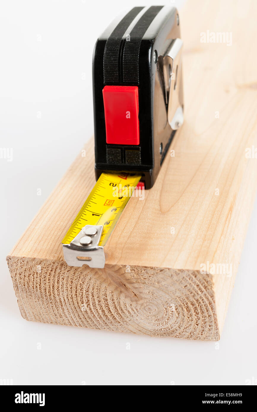 Metal imperial metric tape measure measuring two by four lumber Stock Photo
