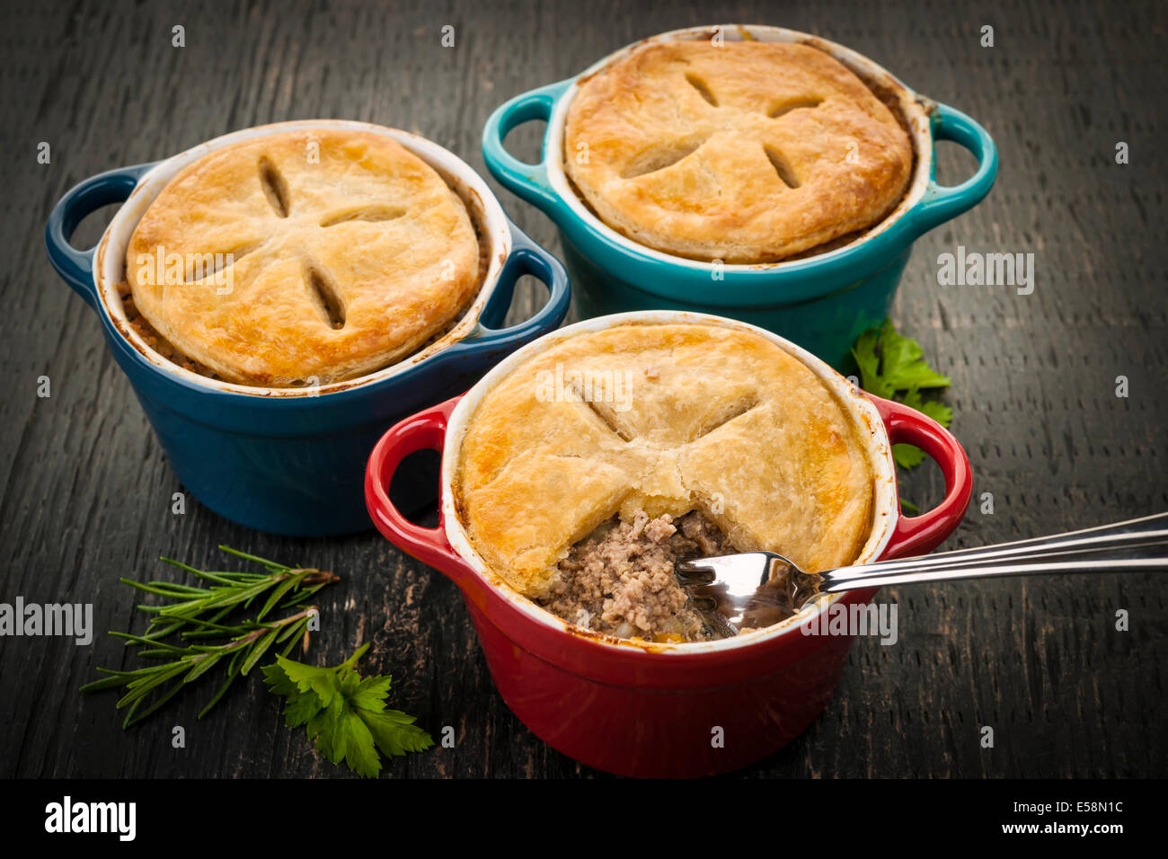 Three homemade gourmet meat pies with fork in ground beef filling on