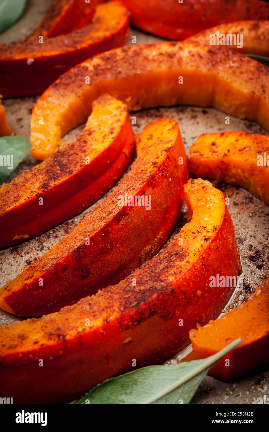 Sliced and spiced raw pumpkin pieces on roasting tray prepared for cooking Stock Photo