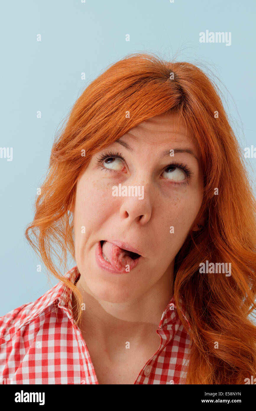 Hipster girl making funny faces, tongue out, looking up Stock Photo