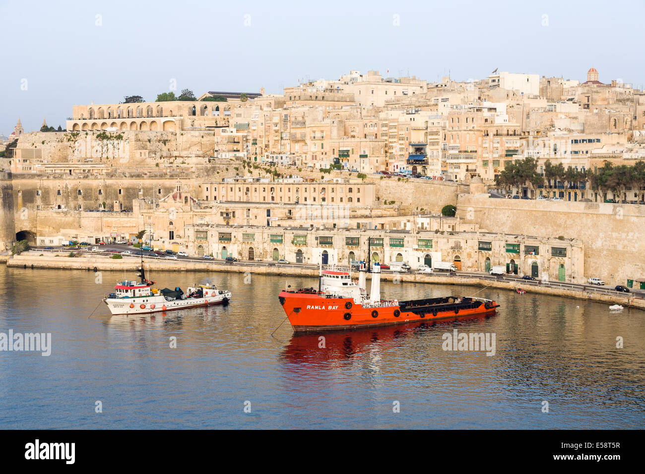 Valletta waterfront Malta with view of the historic old town and two fishing trawlers moored in the Grand Harbour Stock Photo
