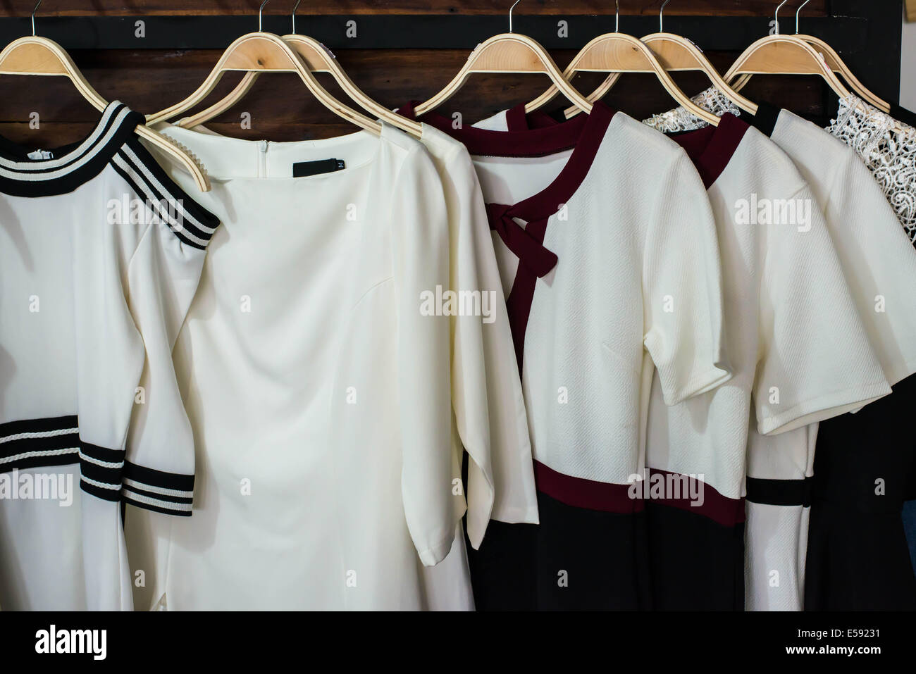 Many white blouses on hangers in the dressing room. Stock Photo