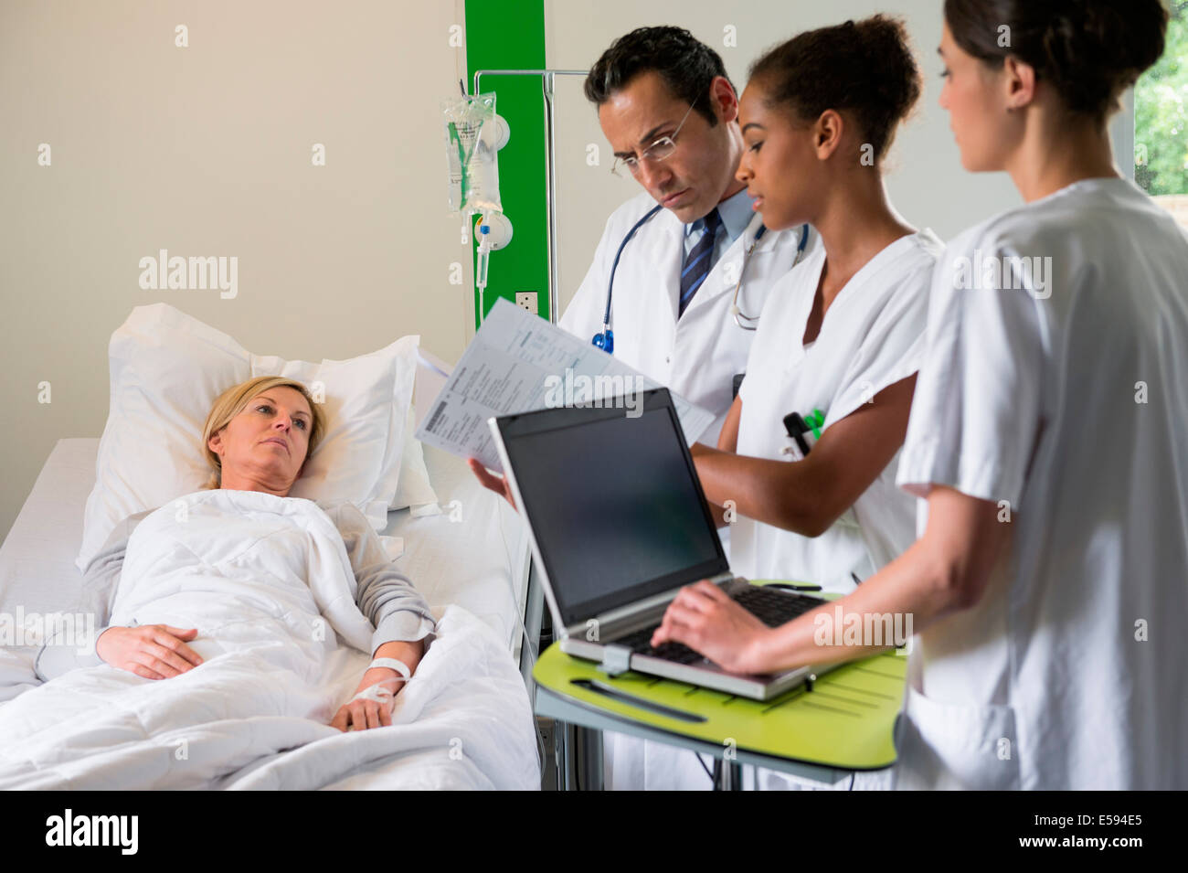 Medical team discussing female patient record on hospital bed Stock Photo