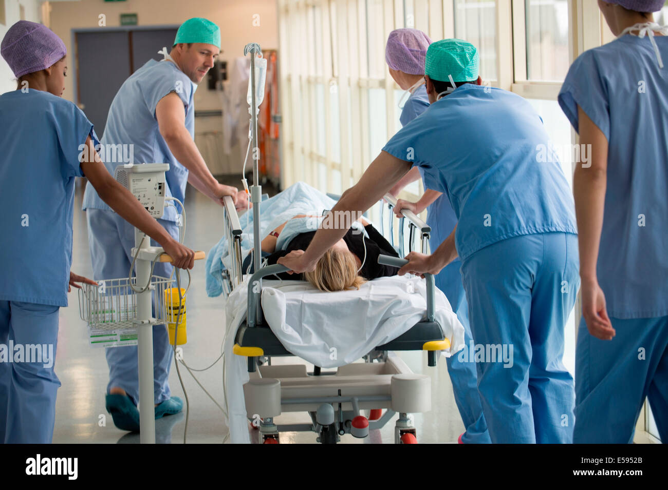 Medical professionals pushing patient on gurney in a hospital Stock
